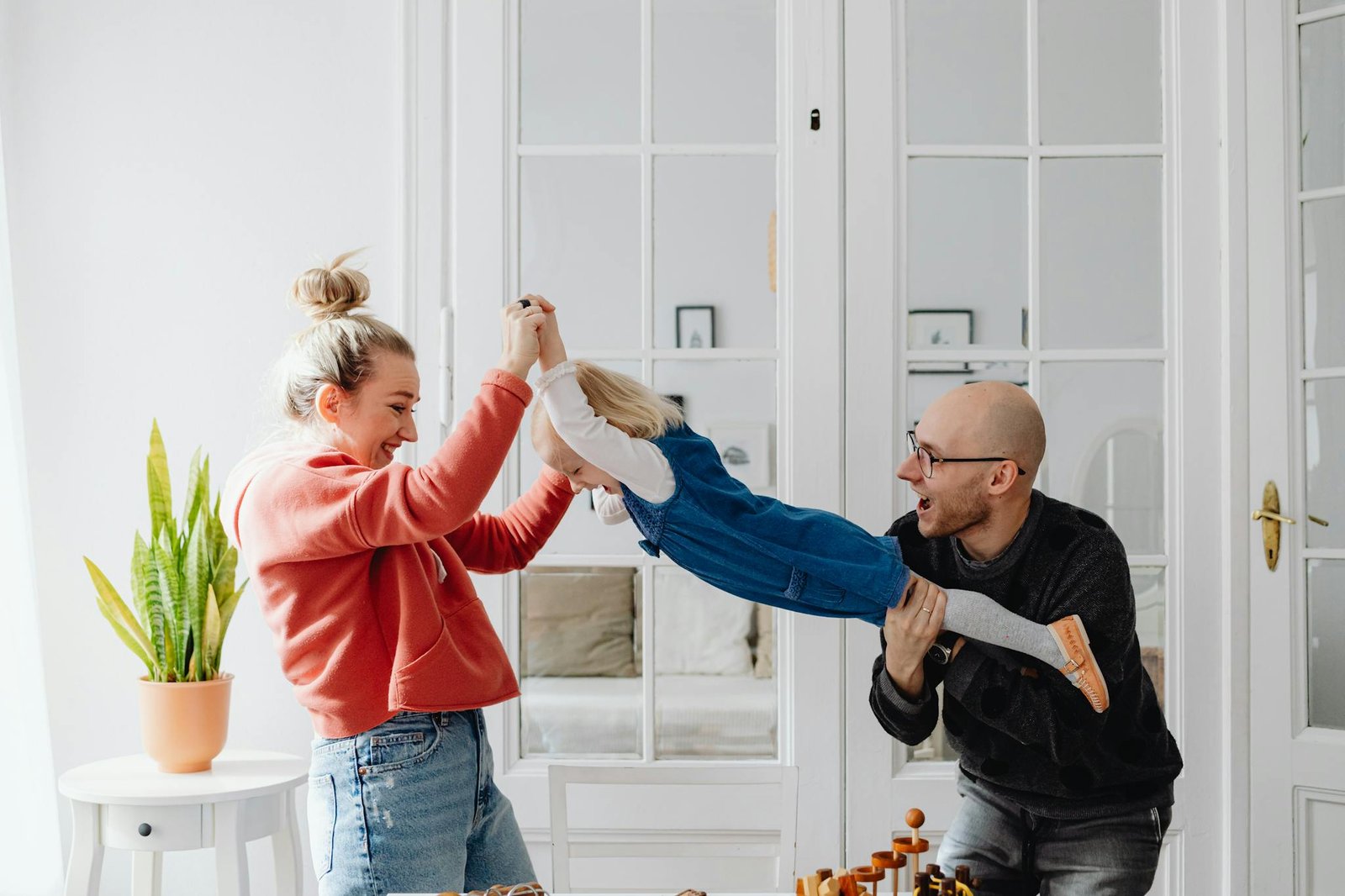 A joyful family moment with parents playing with their daughter indoors.